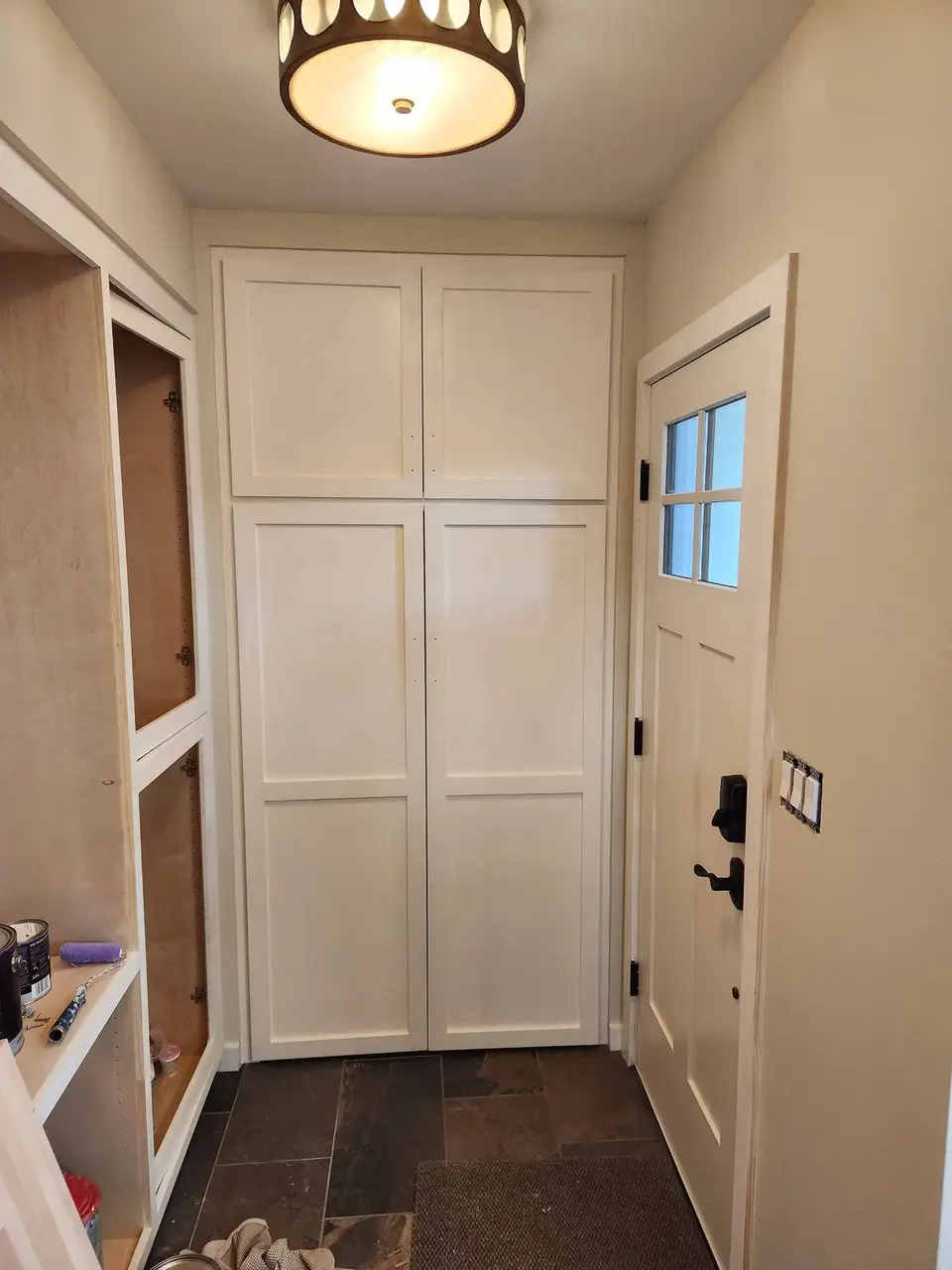 Entry with built-in cabinets, painted panel doors and a slate floor