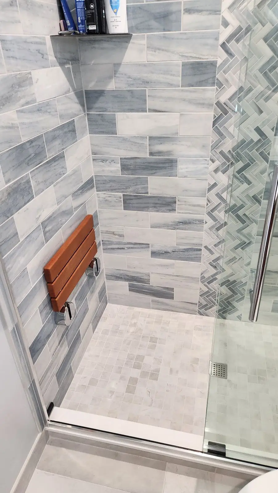Shower with a teak fold-down seat and gray tile