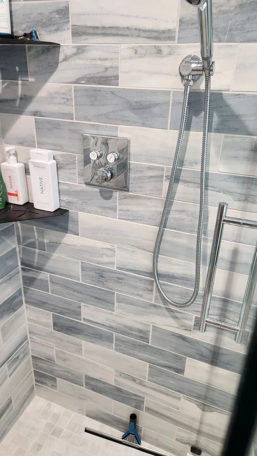 Shower with handheld sprayer and gray marble-look tile